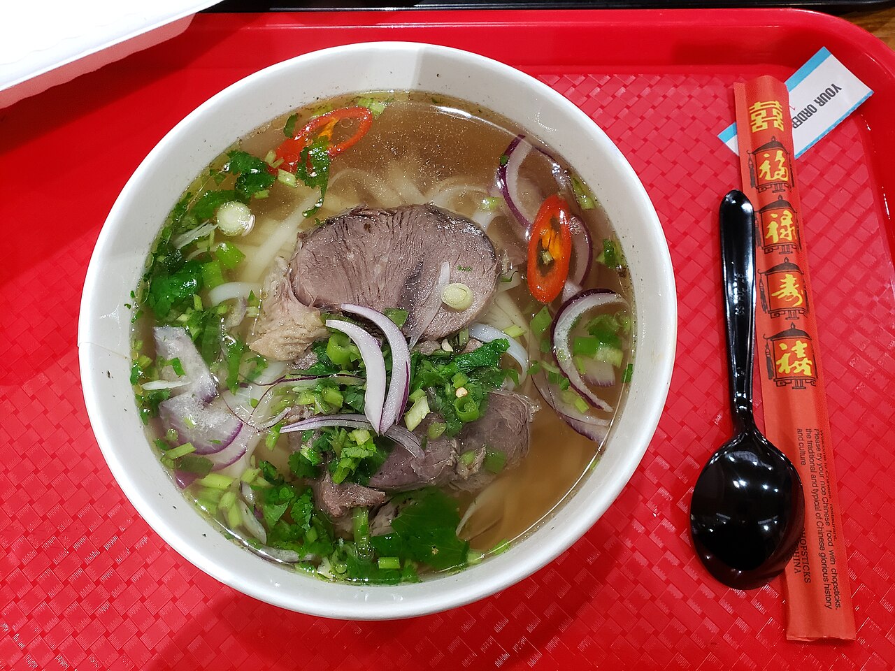 Tô phở bò nước trong với thịt bò chín và hành lá