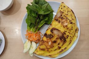 Chiếc bánh xèo vàng giòn ăn kèm rau sống và dưa leo